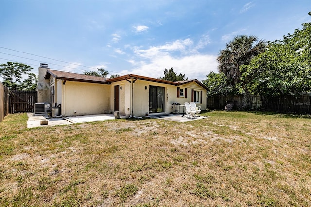 back of property featuring a lawn, a patio, and central air condition unit