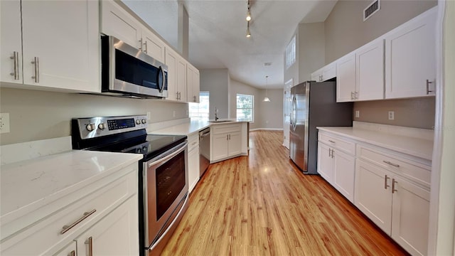 kitchen featuring light wood-type flooring, stainless steel appliances, white cabinets, rail lighting, and sink