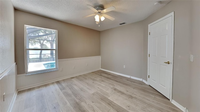 spare room with a wealth of natural light, ceiling fan, light hardwood / wood-style floors, and a textured ceiling