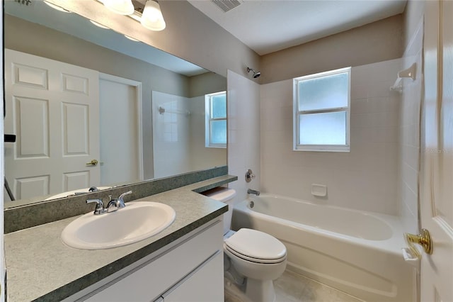 full bathroom with a wealth of natural light, tiled shower / bath, vanity with extensive cabinet space, and toilet