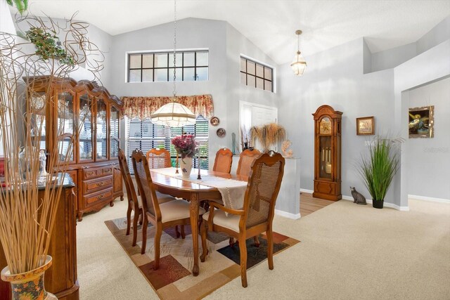 carpeted dining room with high vaulted ceiling