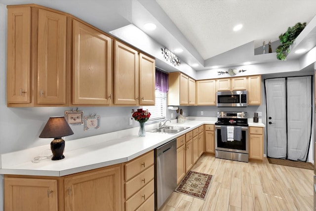 kitchen featuring light brown cabinetry, light hardwood / wood-style flooring, appliances with stainless steel finishes, sink, and lofted ceiling