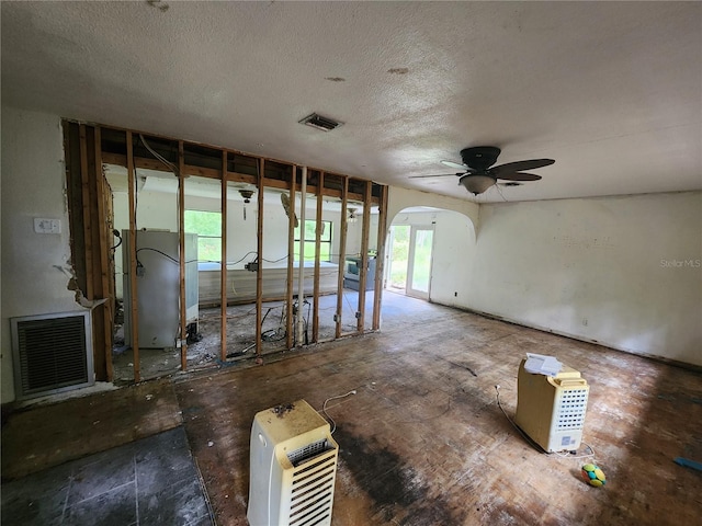 misc room with heating unit, ceiling fan, and a textured ceiling