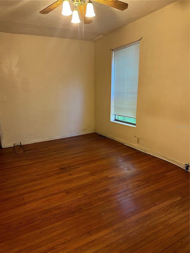 empty room with ceiling fan and dark hardwood / wood-style flooring