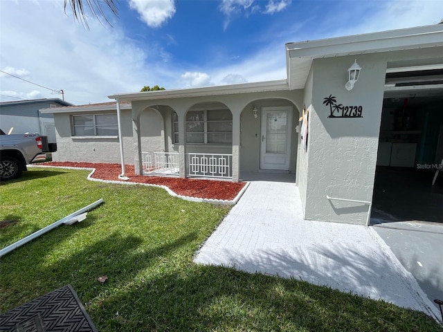 entrance to property featuring a yard and covered porch