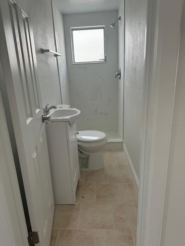 bathroom featuring toilet, vanity, and tiled shower