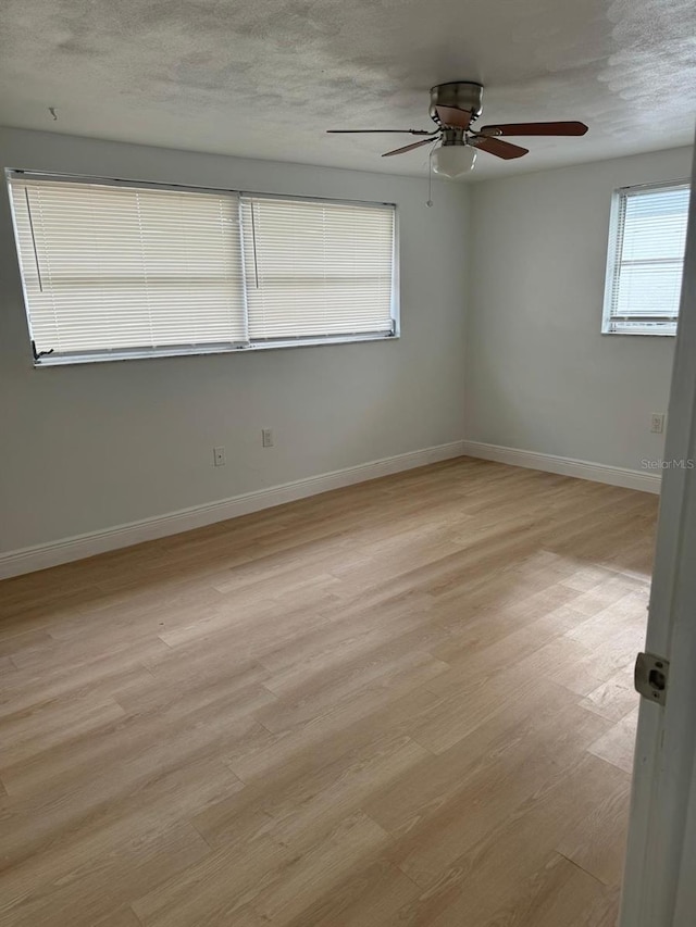 empty room with a textured ceiling, light hardwood / wood-style floors, and ceiling fan