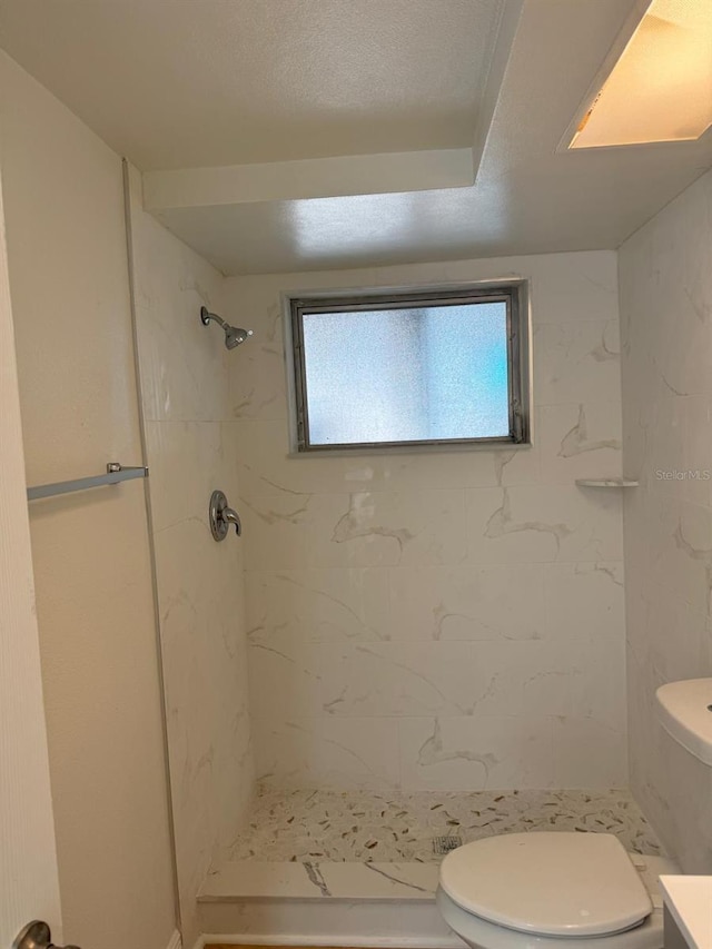 bathroom featuring a tile shower, vanity, and toilet