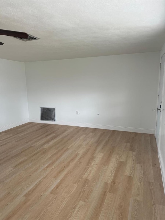 spare room with light wood-type flooring and a textured ceiling