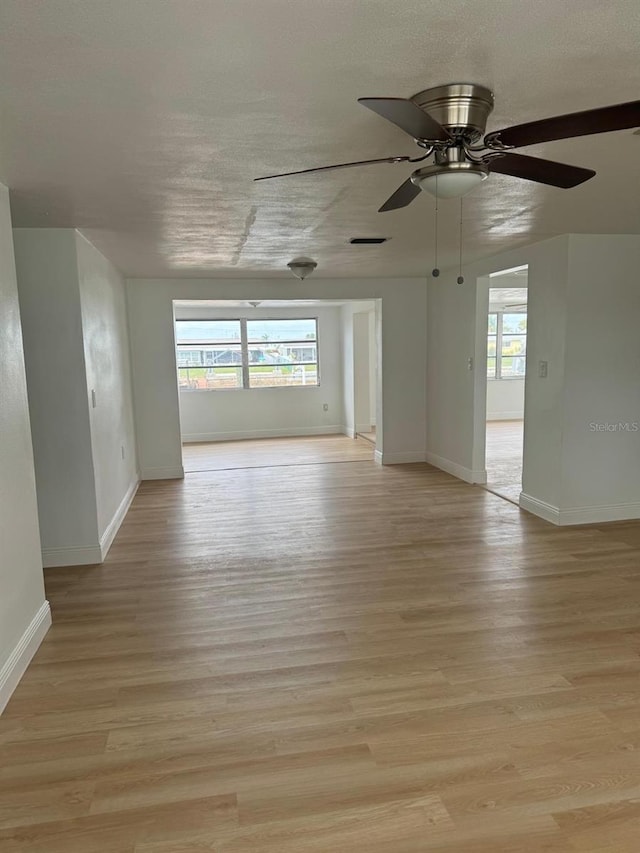 spare room featuring light wood-type flooring, ceiling fan, and a healthy amount of sunlight