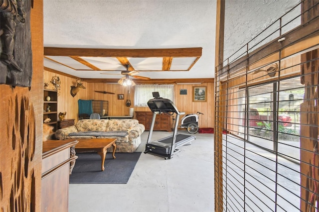 exercise area featuring ceiling fan, wood walls, and a textured ceiling