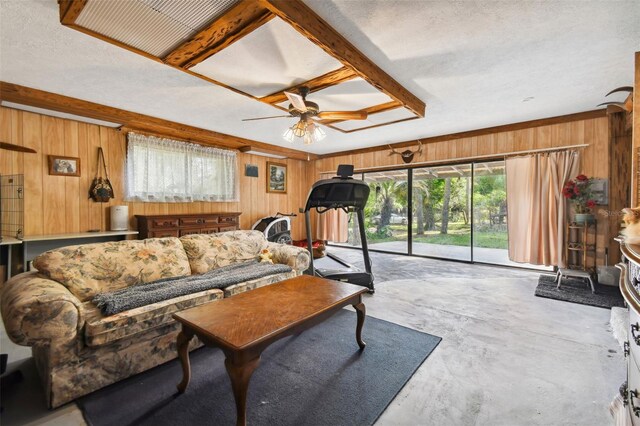 living room with a textured ceiling, wooden walls, concrete flooring, and ceiling fan