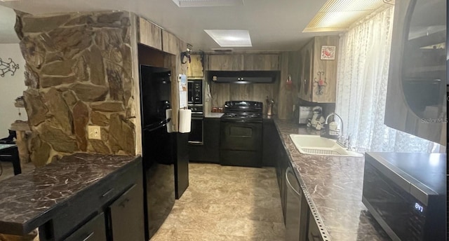 kitchen with dark stone counters, under cabinet range hood, black appliances, and a sink