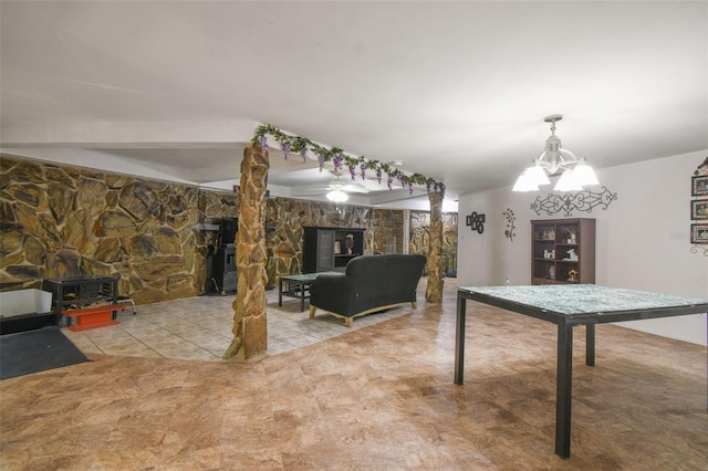 rec room with a wood stove, decorative columns, a chandelier, and light tile patterned floors