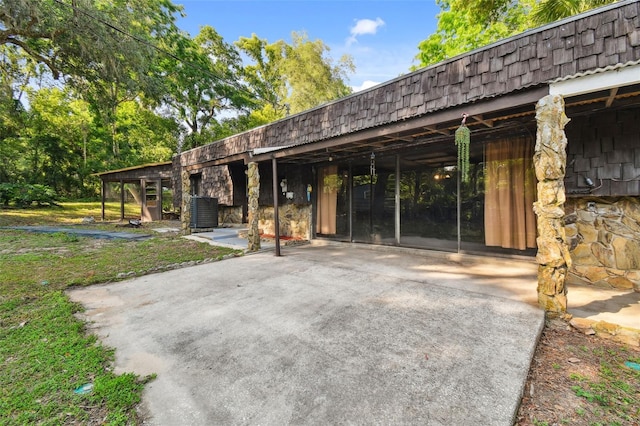 view of front of property with driveway, mansard roof, and stone siding