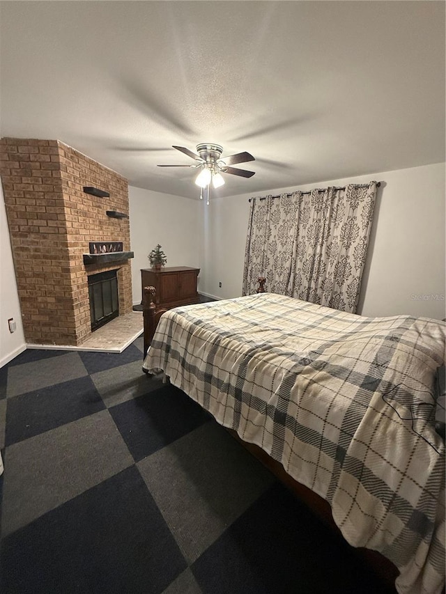 carpeted bedroom featuring baseboards, a textured ceiling, ceiling fan, and a brick fireplace
