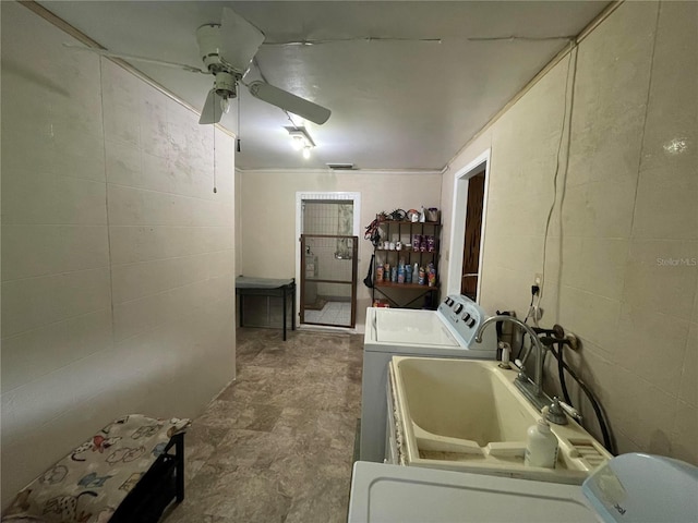 laundry room featuring washing machine and dryer, a sink, a ceiling fan, laundry area, and tile walls