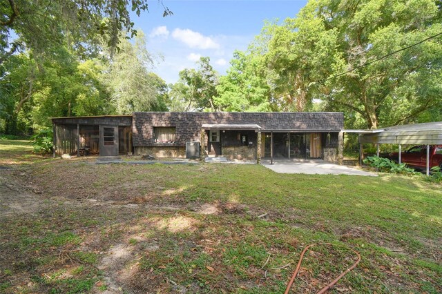 rear view of house with cooling unit and a yard