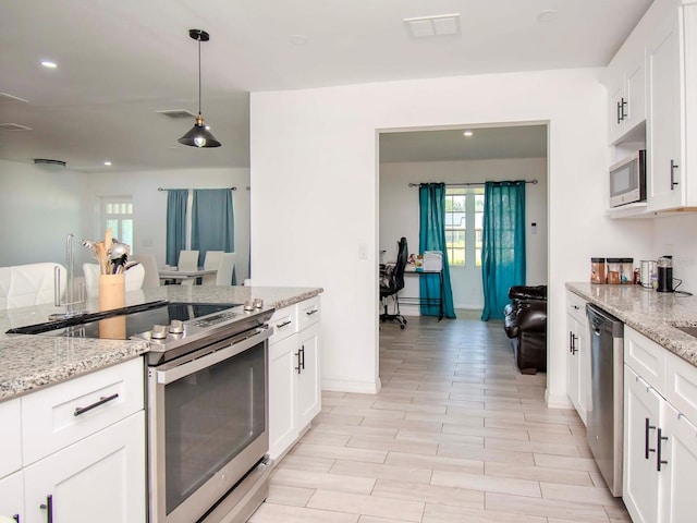 kitchen featuring pendant lighting, light stone counters, light tile floors, white cabinets, and appliances with stainless steel finishes