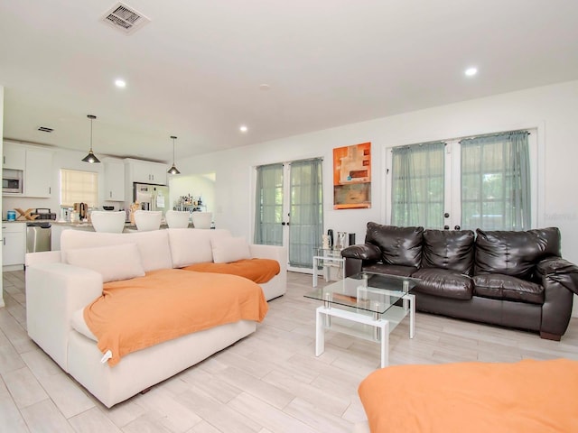 living room featuring a healthy amount of sunlight, light wood-type flooring, and french doors