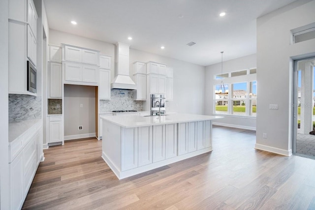 kitchen featuring light countertops, premium range hood, a sink, and light wood-style flooring