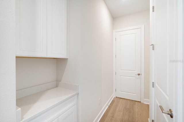 hallway with light wood-type flooring and baseboards