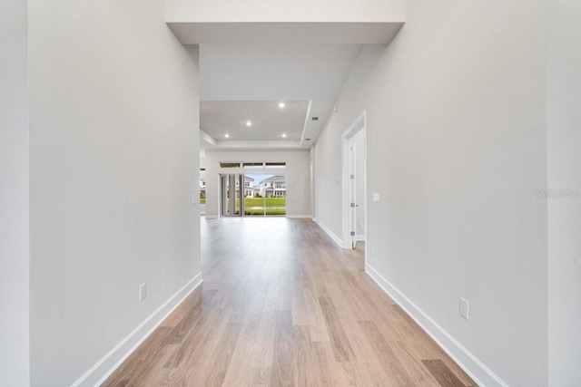 hallway with light wood finished floors, baseboards, and recessed lighting