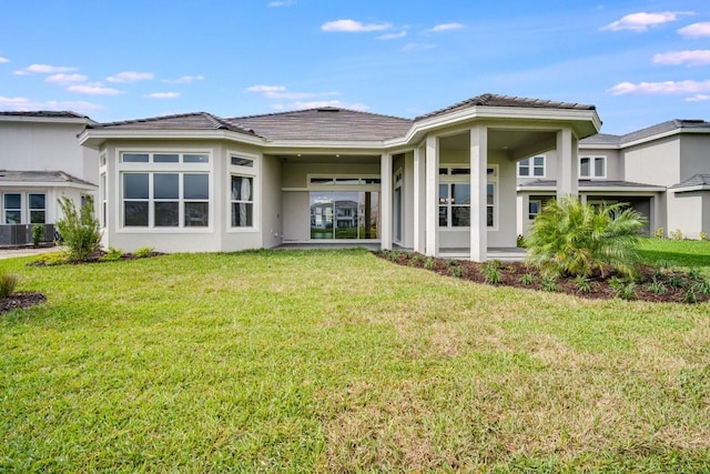 back of house with a tile roof, a lawn, and stucco siding