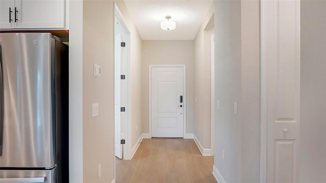 corridor with a textured ceiling and light hardwood / wood-style floors