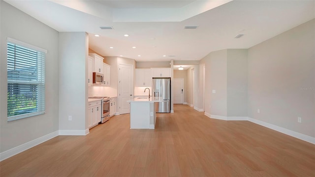 kitchen with light wood-type flooring, stainless steel appliances, a kitchen island with sink, sink, and white cabinets