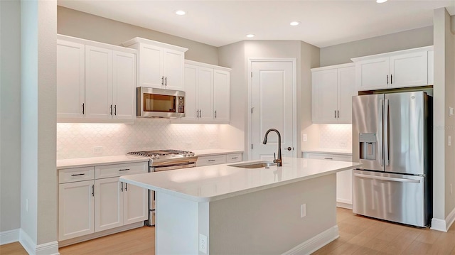 kitchen with a center island with sink, white cabinetry, and stainless steel appliances