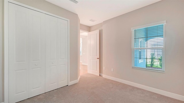 unfurnished bedroom with light carpet and a closet