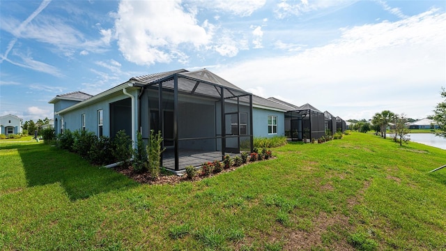 view of side of property featuring a lanai, a lawn, and a water view