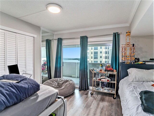 bedroom with hardwood / wood-style floors, a textured ceiling, and crown molding