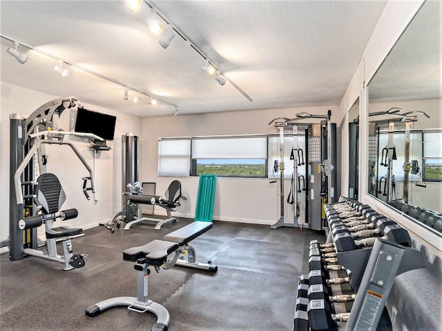 workout area with a textured ceiling and rail lighting