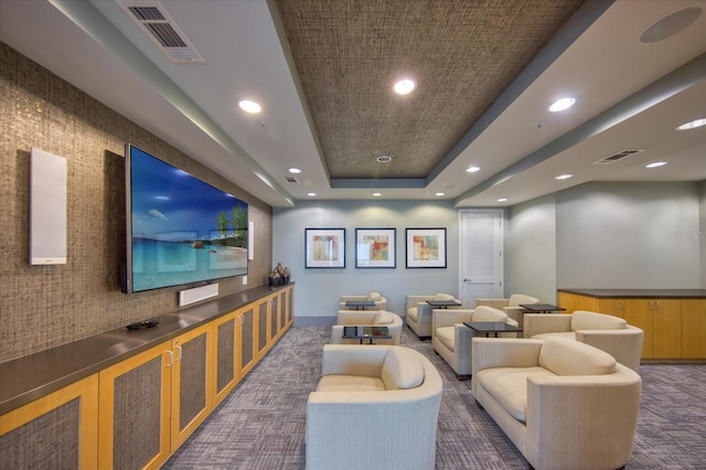 home theater room featuring dark colored carpet and a raised ceiling