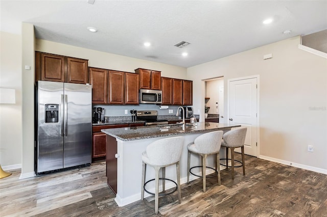 kitchen featuring hardwood / wood-style flooring, sink, appliances with stainless steel finishes, and a kitchen island with sink