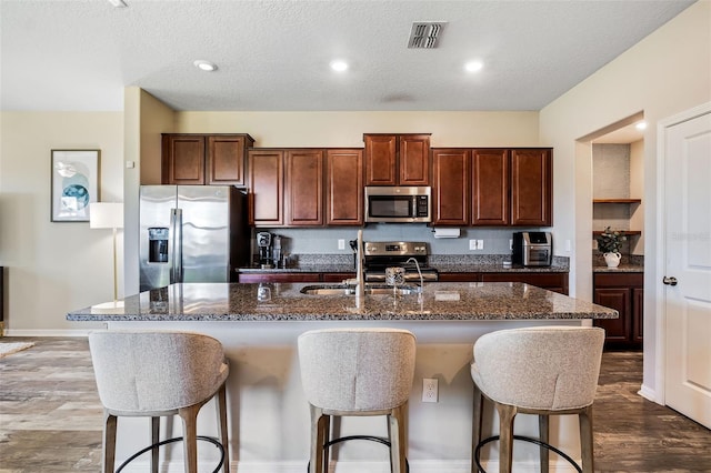 kitchen featuring hardwood / wood-style floors, sink, a kitchen island with sink, a breakfast bar area, and stainless steel appliances