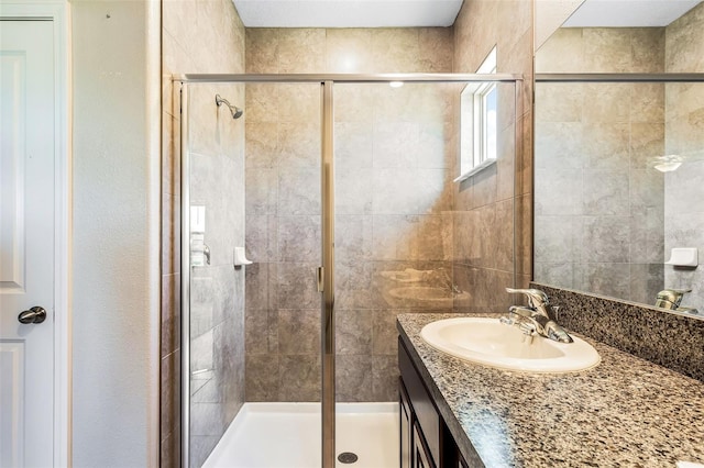 bathroom featuring a shower with door and vanity