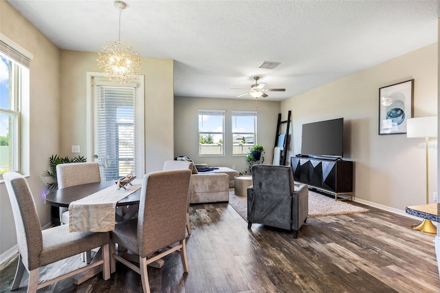 dining space featuring dark hardwood / wood-style floors, plenty of natural light, ceiling fan with notable chandelier, and a textured ceiling