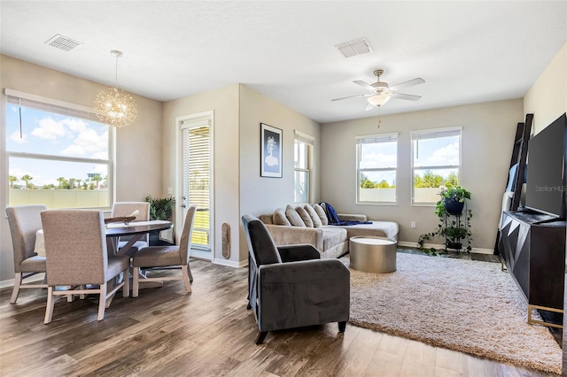 living room featuring ceiling fan with notable chandelier and hardwood / wood-style flooring