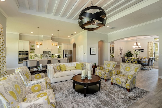 living room with ornamental molding, light wood-type flooring, and a notable chandelier