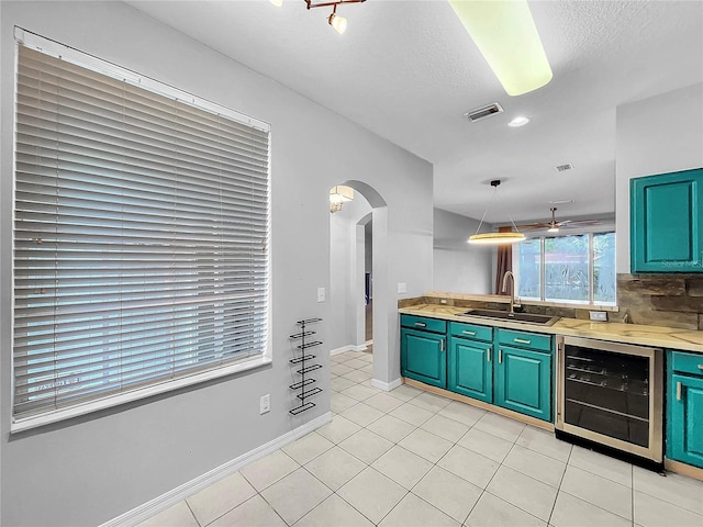 kitchen with light tile patterned flooring, sink, a textured ceiling, pendant lighting, and wine cooler