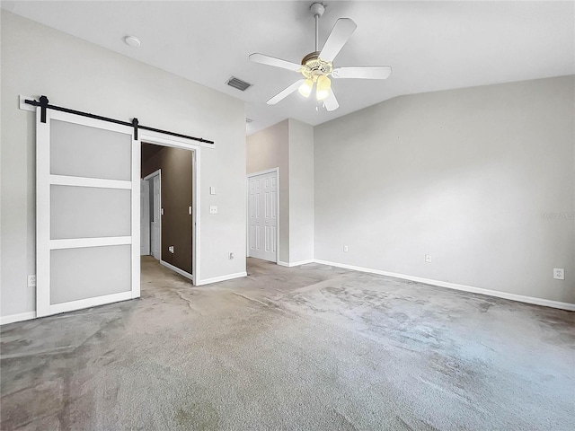 unfurnished bedroom with a closet, carpet, a barn door, vaulted ceiling, and ceiling fan