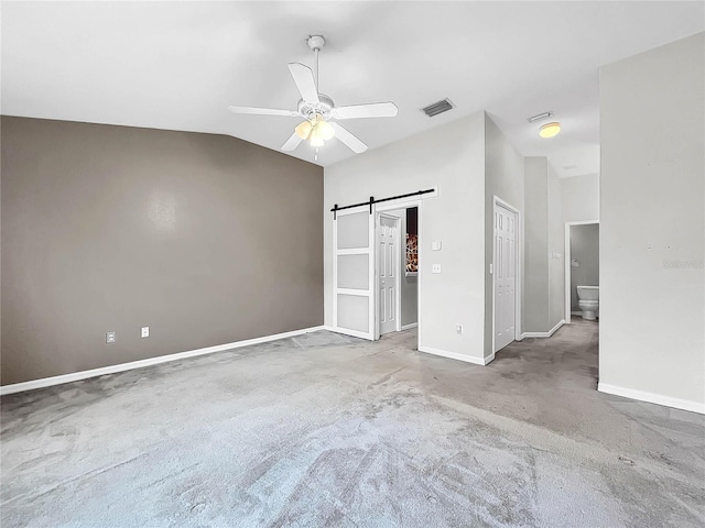 unfurnished bedroom with light carpet, a barn door, connected bathroom, and ceiling fan