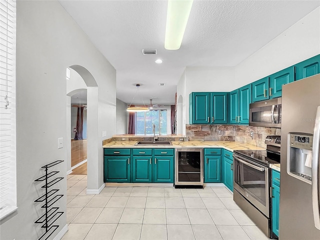 kitchen featuring appliances with stainless steel finishes, sink, pendant lighting, beverage cooler, and light tile patterned floors