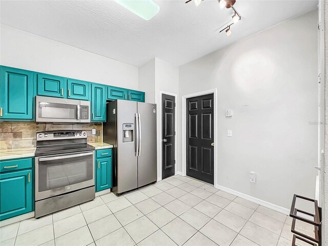 kitchen with track lighting, backsplash, a textured ceiling, light tile patterned flooring, and stainless steel appliances