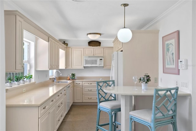 kitchen featuring pendant lighting, white appliances, sink, cream cabinetry, and a kitchen bar