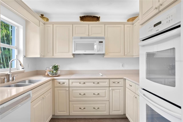 kitchen with cream cabinets, white appliances, and sink