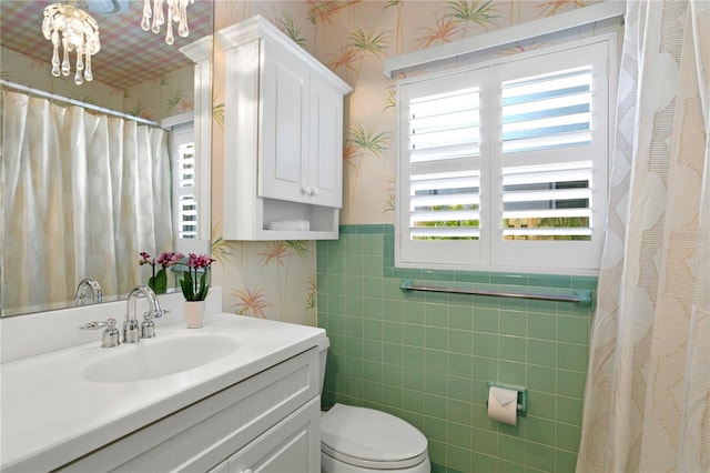 bathroom with vanity, toilet, and tile walls